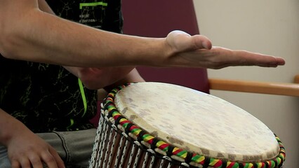 close-up of teacher and student hands playing djembe. African percussion instrument.