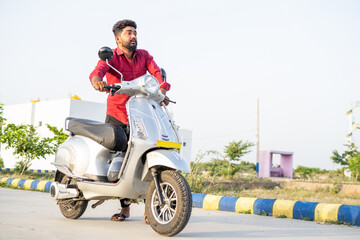 full shot of Worried young man pushing Ev or electric scooter on road druring travel due to low...