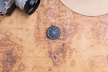 Fototapeta na wymiar Compass on map with vintage camera and hat for traveler