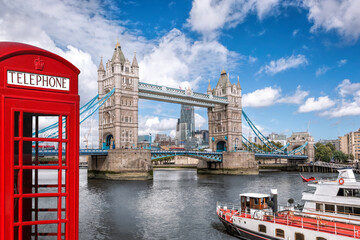 Tower bridge with boat against red phone booth in London, England, UK