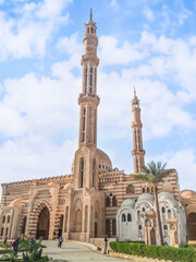 Sharm El Sheikh, Egypt - January 18, 2020: Side view of Al Mustafa Mosque in Sharm El Sheikh. Striped facade of a Muslim temple with two minarets against a blue cloudy sky