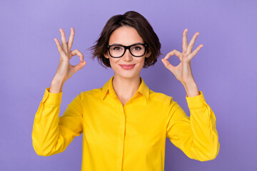 Photo of sweet millennial brunette lady show okey wear spectacles yellow blouse isolated on purple...