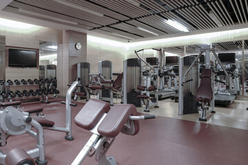 Fototapeta na wymiar Modern light gym. Sports equipment in gym. Barbells of different weight on rack. 