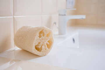 Natural loofah washcloth on the washbasin in the bathroom. Beauty, spa and wellness concept, copy...