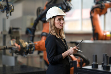 Portrait of female chief engineer in modern industrial factory using tablet.