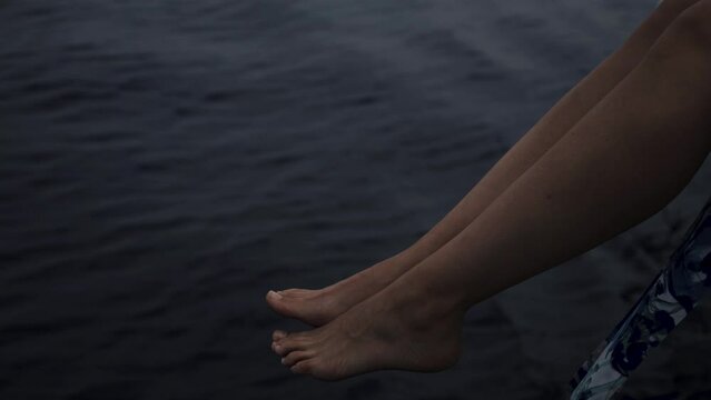Close up of a girl waving her legs above the water out of the yacht 4K