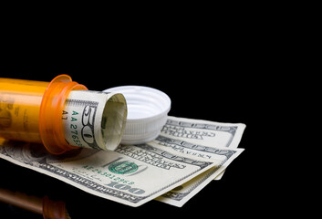 Prescription pill bottle with money on a black background with copy space, isolated.