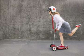Funny businesswoman riding scooter outdoor