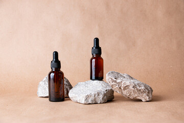 Glass bottles on stones on a pastel background. Cosmetic container mockup with place for text. The concept of natural cosmetics for skin care.
