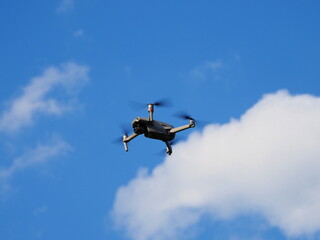 青空で空撮しているドローンを見上げた写真