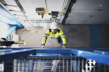 Top view of engineer in industrial factory climbing up the ladder.