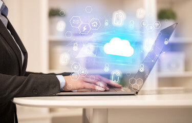 Hands working on laptop with digital icons