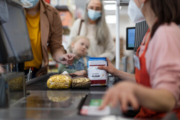Checkout counter hands of the cashier scans groceries in supermarket, during pandemic.