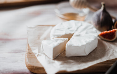Camembert cheese with figs, honey. Round brie or camembert cheese on cutting board white with...
