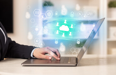 Hands working on laptop with digital icons