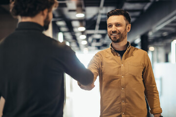 Successful happy businessmen shaking hands to seal deal or make agreement at company office building
