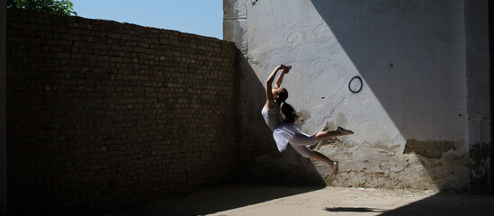 Ballerina dancer ballet dancing and jumping in abandoned building on a sunny summer day