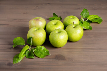 Top view of a composition of fresh ripe green apples and apple tree leaves on a wooden background. Selective focus.