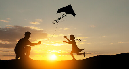 Happy family on the field. Father and daughter playing with a kite while running on meadow on the...