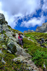 Fototapeta premium Escursionista donna con occhiali da sole scende dal sentiero EE che porta al Bivacco Combi e Lanza, Alpi Lepontine, Devero, Italia