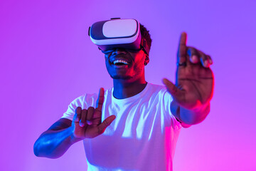 Cool black guy in VR glasses exploring cyberspace, touching imaginary screen, playing virtual...