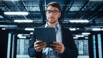 Successful Data Center IT Specialist Using Tablet Computer. Server Farm Cloud Computing Facility with System Administrator Working. Data Protection Engineering Network for Cyber Security.