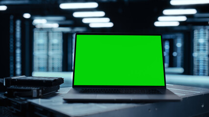 Laptop Computer with Green Screen Chroma Key Mock Up Display Stands on a Table. In the Background...