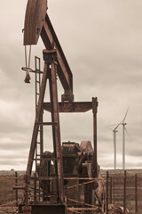 Fototapeta na wymiar Oil pumping machine and windmills. Petroleum extraction. Global warming