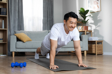 Cheerful asian man exercising alone at home