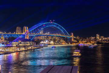 Fototapeta na wymiar Colourful Light show at night on Sydney Harbour NSW Australia. The bridge illuminated with lasers and neon coloured lights 