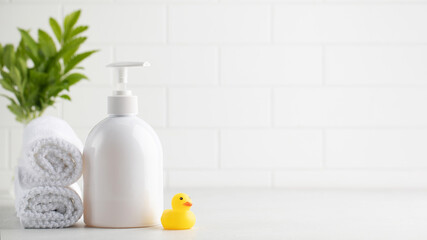 Dispenser bottle of children shampoo towels and small rubber duck in bathroom