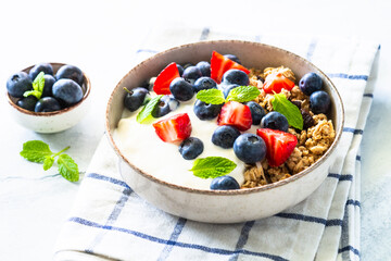 Healthy breakfast. Yogurt with granola and fresh berries at white table.