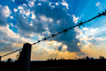 Barbed wire fence with silhouette sky and cloud