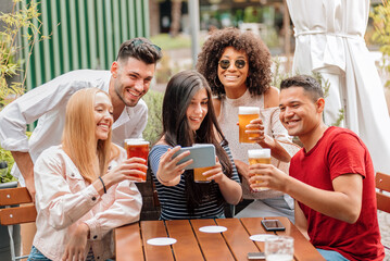Group of diverse friends taking selfie while having a beer