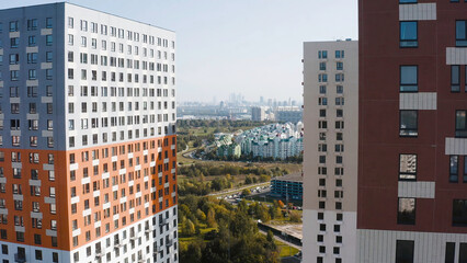Top view of multi-colored residential complexes in city. Action. Beautiful panorama of city opens from upper floors of modern residential complex. Bright residential complex on Sunny day