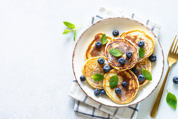 Pancakes with fresh blueberries and honey at white table. Healthy breakfast or dessert. Top view with copy space.