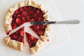 Pieces of homemade strawberry galette pie on white table. Top view