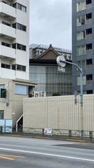Traditional temple house rooftop peeking between the new modern buildings, cityscape Tokyo year 2022 June 14th