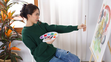 Creative of art concept, Young asian woman hold paintbrush in front of canvas to measure proportion