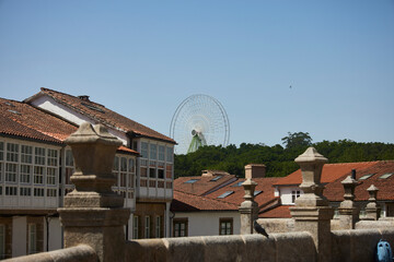 Santiago de Compostela (Spain), June 14, 2022. Ferris wheel. Fair attraction seen between the facade of some old houses.