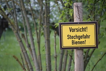 Black and yellow warning sign 'Attention! Danger of stings. Bees!' in spring (horizontal), Hildesheim, Lower Saxony, Germany