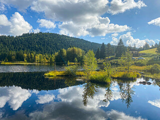 Beautiful clouds reflection in water of Lispach lake in the La Bresse, Vosges