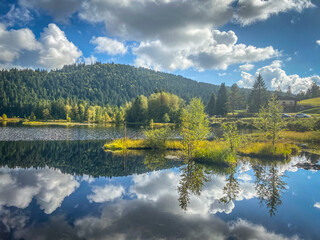 Beautiful clouds reflection in water of Lispach lake in the La Bresse, Vosges