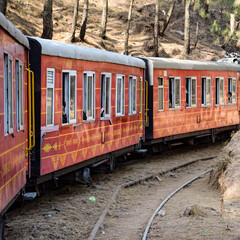 Obraz premium Toy Train moving on mountain slopes, beautiful view, one side mountain, one side valley moving on railway to the hill, among green natural forest. Toy train from Kalka to Shimla in India