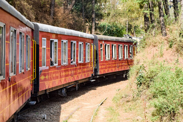 Obraz premium Toy Train moving on mountain slopes, beautiful view, one side mountain, one side valley moving on railway to the hill, among green natural forest. Toy train from Kalka to Shimla in India