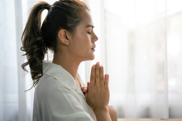 Beautiful woman praying with hands together on white at home. Asian woman pray for god blessing wishing better life.