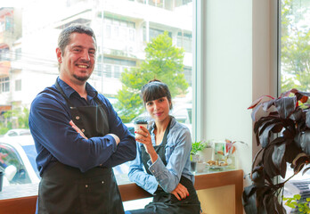 Obraz premium Caucasian young man and woman who owns a barista coffee shop. Successful talking, smiling, inside the coffee shop.