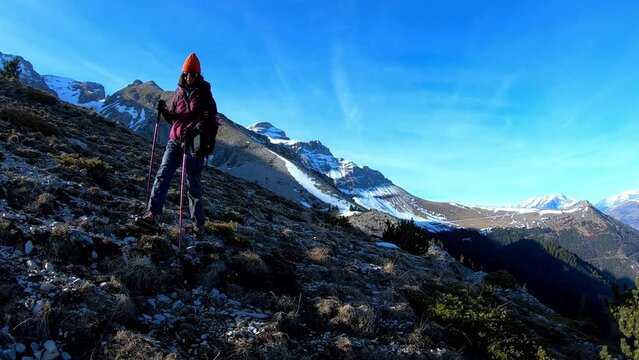 Young caucasian woman hiking down a mountain with hand sticks. Mountain with snow in background.
Location : D&eacute;voluy, Hautes Alpes, France, Alps
February 2022