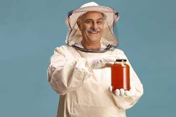 Bee keeper in a uniform holding a honey jar