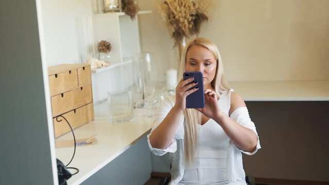 young blonde woman in a wheelchair filming a video blog on a smartphone